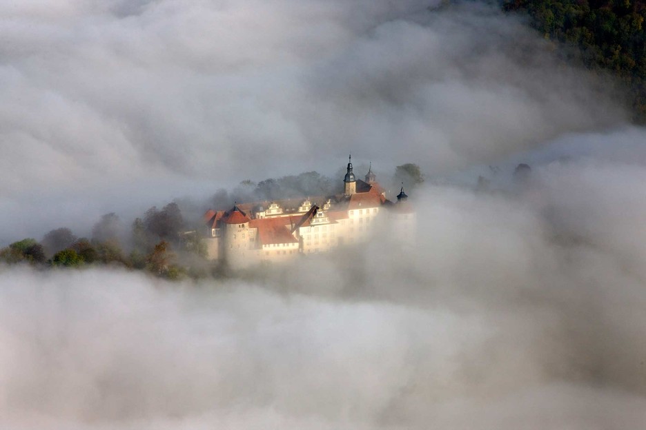 Luftaufnahme des Schloss Langenburg von dichtem Nebel umgeben.