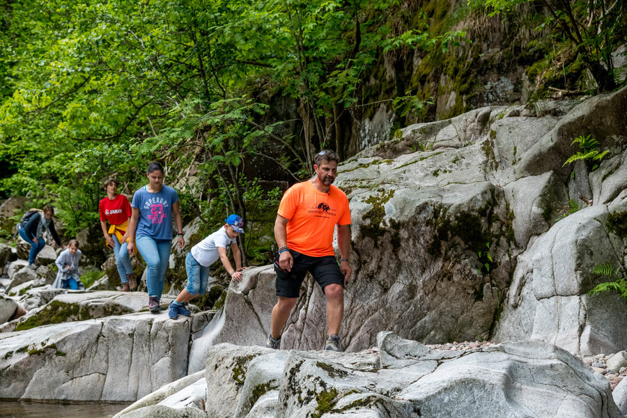 Ein Guide führt die Kinder und Erwachsenen über große Steine und Felsen entlang eines Flusses.