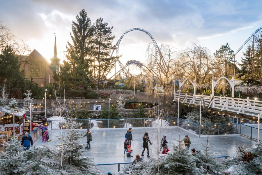 Die Eislauffläche im winterlichen Europa-Park entführt Gäste in einen Winterwald mit weißen Nadelbäumen.